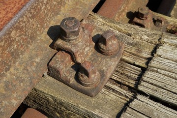 Rusty hexagon nut and bolts on an old weathered railroad sleeper