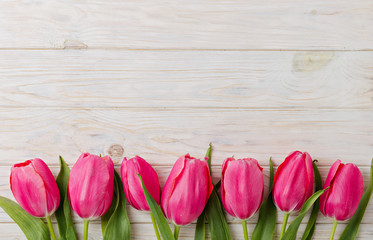 Bouquet of pink tulips on a light wooden background. View from above.
