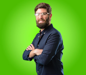 Young hipster man with big beard with crossed arms confident and happy with a big natural smile laughing over green background