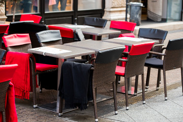 tables and chairs on the street near a cafe with posted plaids for visitors