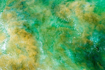 Fototapeta na wymiar Top aerial view of blue green waves crashing on rocky Australian coastline. Summer seascape with ocean waves. Travel concept background