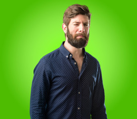 Young hipster man with big beard with sad and upset expression, unhappy over green background