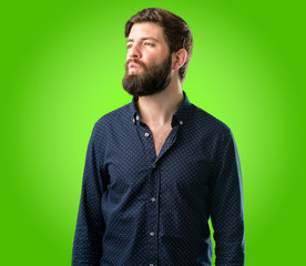 Obraz premium Young hipster man with big beard expressing love, blows kiss at camera, flirting over green background