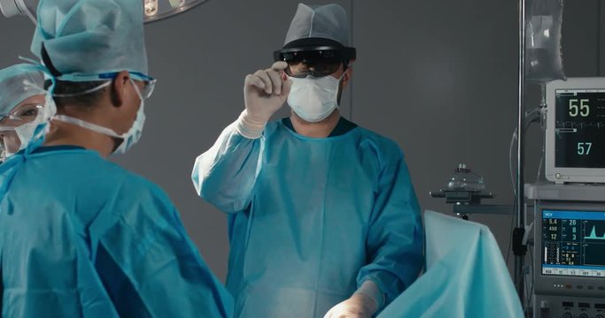 MED Team of surgeons using augmented reality holographic hololens headset while operating in modern operation theater. 4K UHD 60 FPS SLO MO