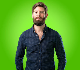 Young hipster man with big beard confident and happy with a big natural smile looking at camera over green background