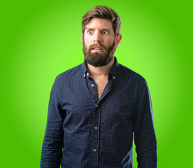 Obraz premium Young hipster man with big beard making funny face fooling over green background