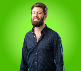 Young hipster man with big beard confident and happy with a big natural smile laughing over green background