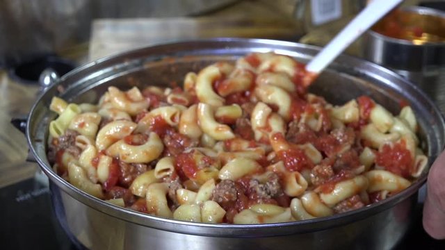 Stirring pasta with tomatoes and hamburger
