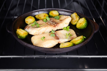 Frying pan with tasty fish fillets in oven