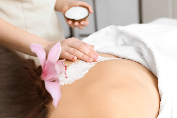 Obraz na płótnie Canvas Young woman having body scrubbing procedure with sea salt in spa salon, closeup