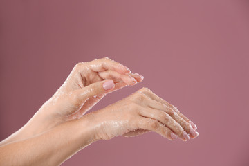 Fototapeta premium Young woman applying natural scrub on hands against color background