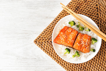 Fish fillet served with rice and broccoli on wicker coaster