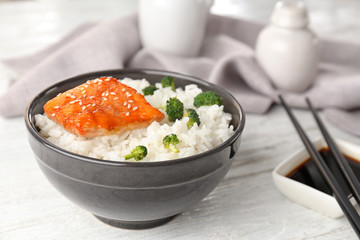 Fish fillet served with rice in bowl on wooden background