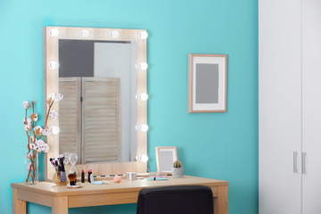 Decorative cosmetics and tools on dressing table near mirror in makeup room