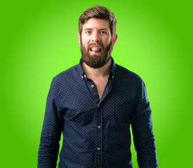 Young hipster man with big beard sticking out tongue at camera at sign of disobedience, protest and...