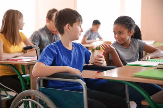 African American girl with boy in wheelchair at school