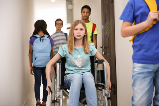 Sad girl in wheelchair at school corridor
