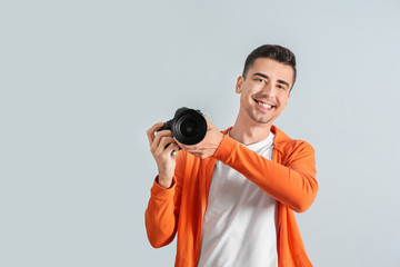 Male photographer with camera on light background