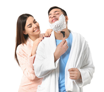 Young man shaving and his girlfriend on white background