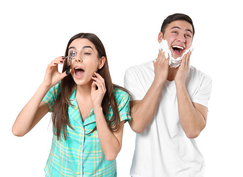 Young man shaving and his girlfriend with eyelash curler on light background
