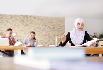 Muslim woman in traditional clothes studying indoors