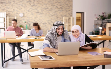 Muslim students in traditional clothes studying indoors