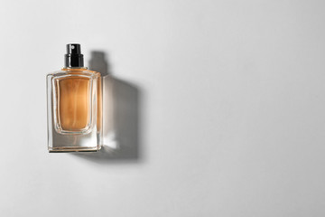 Bottle of perfume on light background, top view