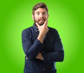 Young hipster man with big beard scared in shock, expressing panic and fear over green background