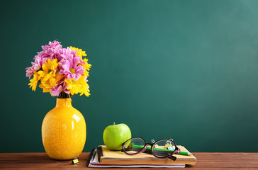 Bouquet of flowers and notebooks with eyeglasses on table. Teacher day celebration
