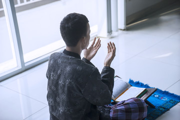 Male muslim prays to GOD after reading Quran