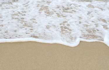 The white waves bounce up to the fine sand.