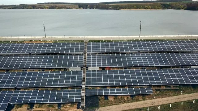 Solar panels near the river. Power station. Blue solar panels. Alternative source of electricity. Solar farm.