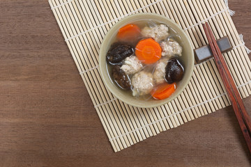 pork chop clear soup in a ceramic bowl on wooden table with copy space, top view. homemade style healthy food concept.