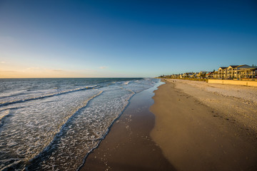 Beautiful colorful sunset summer view to the calm great ocean with pure sandy beach and a lovely empty wooden jetty lighten the night at a public boulevard, Glenelg Jetty, Adelaide, South/ Australia
