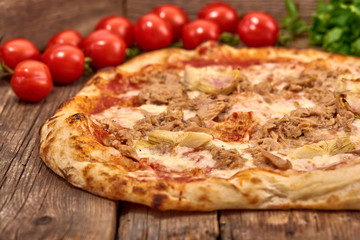 Homemade fresh delicious gourmet pizza whit garlic, tuna and artichokes,Tasty italian pizza isolated on wooden table,Close up with selective focus