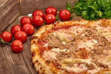 Homemade fresh delicious gourmet pizza whit garlic, tuna and artichokes,Tasty italian pizza isolated on wooden table,Close up with selective focus