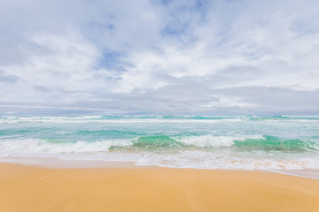 Fototapeta na wymiar Enjoy this amazing sea view with pure sandy beach and crystal clear blue water a few waves coming to the shore at a lonely empty place on Tasmania, Australia