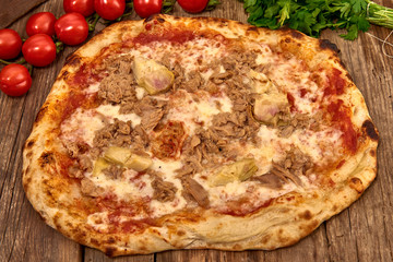 Homemade fresh delicious gourmet pizza whit garlic, tuna and artichokes,Tasty italian pizza isolated on wooden table,Close up with selective focus