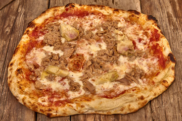 Homemade fresh delicious gourmet pizza whit garlic, tuna and artichokes,Tasty italian pizza isolated on wooden table,Close up with selective focus