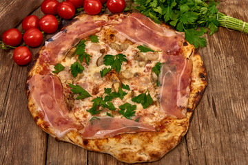 Homemade fresh delicious gourmet pizza whit shrimps, porcini mushrooms, speck, garlic and fresh parsley,Tasty italian pizza isolated on wooden table,Close up with selective focus