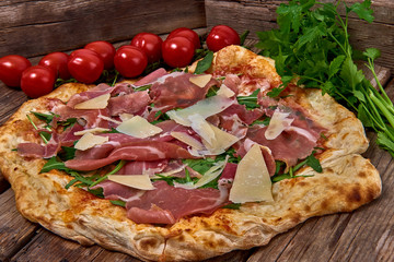 Homemade fresh delicious gourmet pizza whit grana cheese, raw ham and rocket ,Tasty italian pizza isolated on wooden table,Close up with selective focus