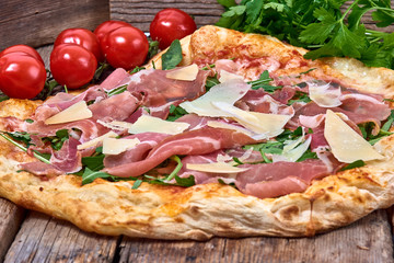 Homemade fresh delicious gourmet pizza whit grana cheese, raw ham and rocket ,Tasty italian pizza isolated on wooden table,Close up with selective focus
