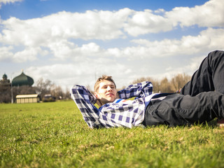 Naklejka na ściany i meble young man close up portrait lying on the grass on a sunny summer day