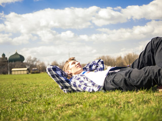 young man close up portrait lying on the grass on a sunny summer day