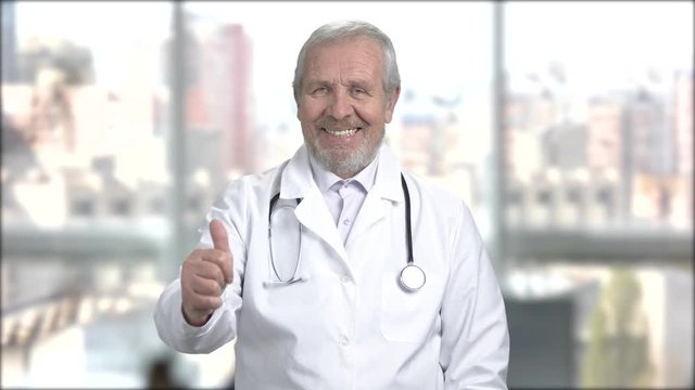 Senior handsome doctor gesturing thumb up. Caucasian male doctor giving thumb up sign. Symbol of success.