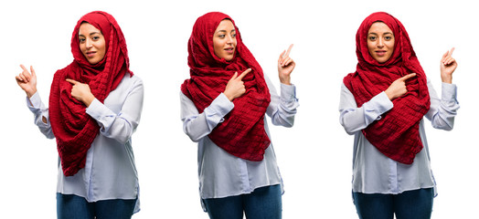 Fototapeta premium Arab woman wearing hijab pointing away side with his finger isolated over white background