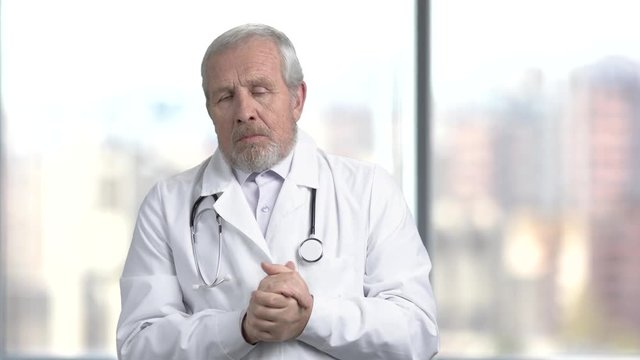 Confused senior doctor, blurred background. Depressed medical worker in white coat gesturing with hands in frustration. Bad news to patient.