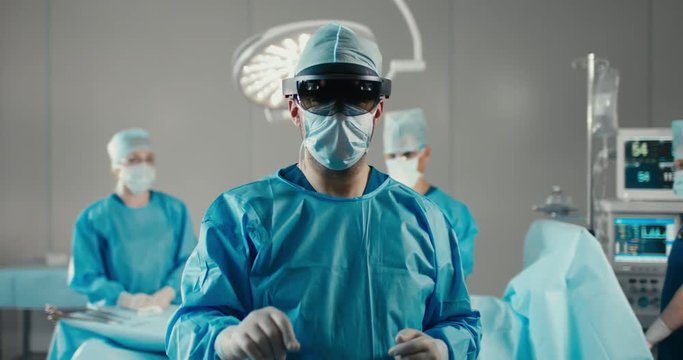 Front view half portrait of surgeon using augmented reality holographic hololens headset, preparing for operation in modern operation theater. 4K UHD 60 FPS SLO MO