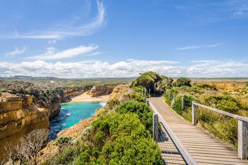 Bright sunny summer coast view to a beautiful sandy beach bay and rocky erosion sand limestone cliff of Great Ocean Road, walking at Loch Ard Gorge, Port Campbell National Park, Victoria/ Australia