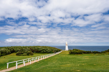 Fototapeta na wymiar Sunny beautiful summer coast view a white bright light station at Otway National Park with green area and the blue waves of the Bass Strait sea, Cape Otway Lighthouse, Victoria, Melbourne, Australia